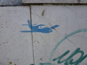 kleines Flugzeug in Blau an getaggter Wand - Detail